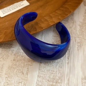 Close-up of a dark blue marble resin cuff bangle on a rustic wooden tray texture
