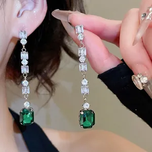 Elegant silver tassel earrings featuring green emerald-cut stones and sparkling cubic zirconia