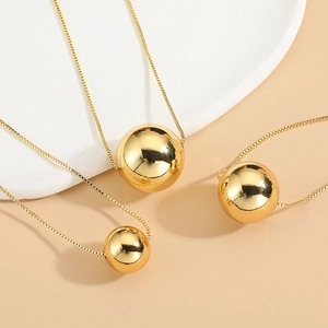 Collana con pendente a sfera dorata in tre dimensioni su vassoio decorativo lucido