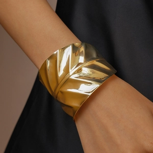 Macro detail of wide gold cuff bracelet featuring crinkled metallic leaf texture
