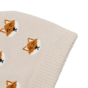 Close-up of beige knitted fabric featuring cute orange fox patterns and soft texture