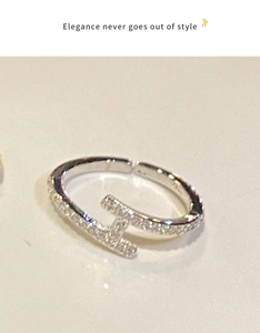 Détail d'une bague ouverte en forme de H argentée sertie de zircons cubiques brillants