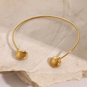 Detailed view of gold shell choker necklace with embossed textures on a natural stone