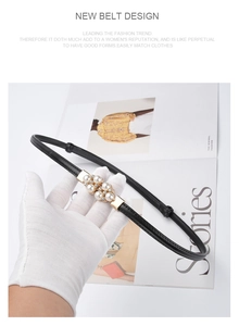 Detail of thin black leather belt featuring elegant pearl and rhinestone buckle design
