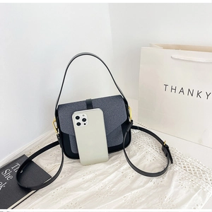 Close-up of the small crossbody bag next to a smartphone for size scale comparison