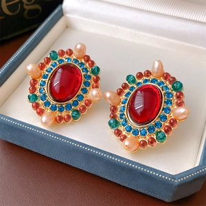 Detail of vintage gold earrings with red gems and pearls in a velvet jewelry box