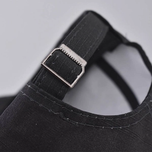 Macro detail of the black cotton baseball cap showing adjustable silver metal buckle strap