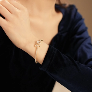 Gros plan d'un bracelet papillon doré orné de zircons sur un poignet avec du velours bleu