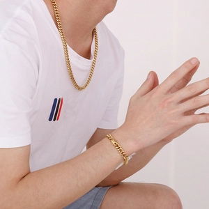 Close-up of gold cuban link necklace and bracelet set worn by male model on a clean background
