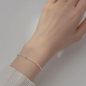 Minimalist s925 silver necklace with multi-colored rainbow beads worn on a female wrist