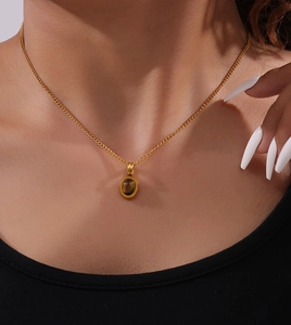 Detail of tiger eye stone pendant on gold cuban chain necklace worn by a model