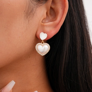 Close-up of double heart drop earring with rhinestones and pearl inlay on ear