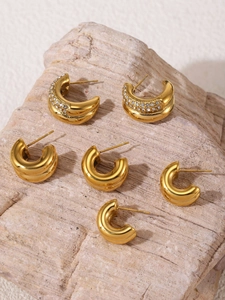 Detailed view of three pairs of 18K gold-plated C-shaped earrings with rhinestones on stone