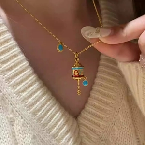Macro detail of vintage Tibetan prayer wheel pendant with colorful enamel and gold chain