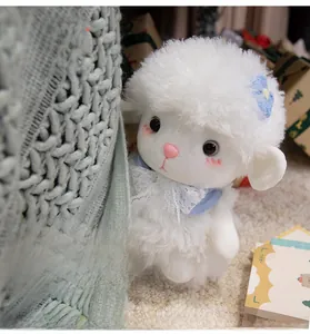 Close-up of cute white plush lamb with blue flower and lace collar hiding behind a blanket