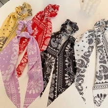 Detailed flat lay of paisley pattern fabric hair scrunchies in five vibrant colors