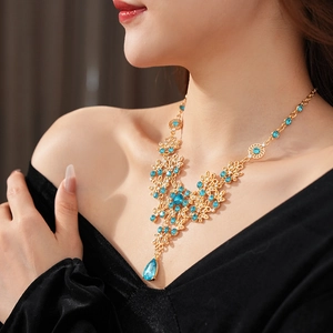 Exquisite gold flower necklace with blue teardrop crystal pendant on a model