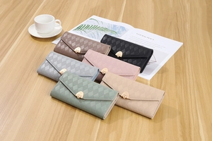 Six colors of quilted PU leather envelope wallets displayed on a wooden desk with a coffee cup