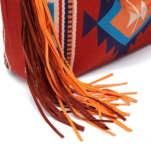 Detail of bohemian woven tote bag showing red geometric pattern and long colorful tassels
