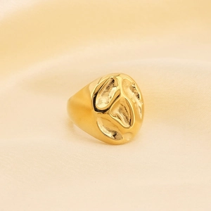Détail macro d'une bague dorée texture lave irrégulière sur fond de soie beige élégant