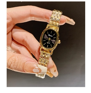 Close-up of golden steel band watch with elegant oval black dial and quartz movement