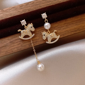 Detail of asymmetric rocking horse earrings with gold plating, zircon, and pearls
