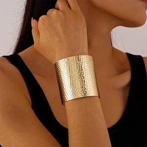 Detailed view of wide gold hammered cuff bracelet with textured metallic surface on wrist