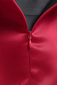 Close-up of invisible zipper and red glossy fabric on the back of the elegant dress