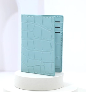 Detail of light blue faux leather card holder with crocodile pattern and contrast stitching