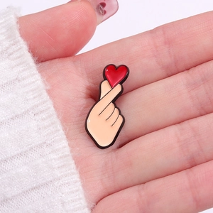 Cute enamel pin with hand heart gesture and red heart detail for clothing and bags