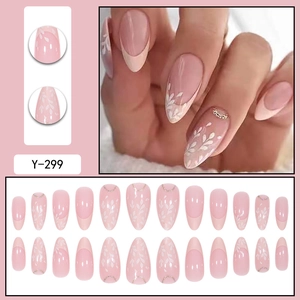 Macro detail of nude almond press-on nails with white leaf art and golden glitter lines
