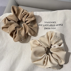 Detailed view of satin scrunchies with rhinestones in beige and champagne tones