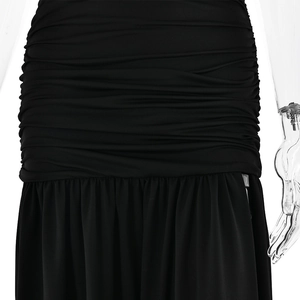Detail of the high-slit black dress showing pleated waist design and flowing hemline
