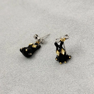 3D black enamel rabbit earrings with silver bow and yellow rhinestones on grey surface