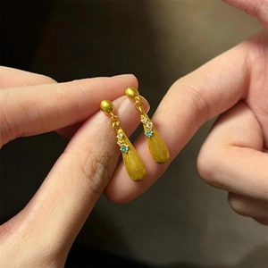 Detail of vintage gold-tone drop earrings with emerald green gemstones and zircon accents