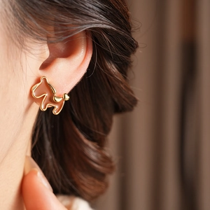 Close-up detail of 18K gold plated horse stud earring with pearl and brown enamel