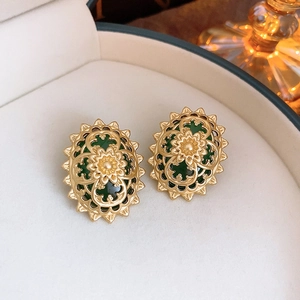 Macro detail of vintage gold hollow flower earrings with green center in jewelry box