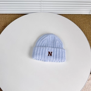 Close-up of light blue ribbed knit hat with brown letter N embroidery and soft texture