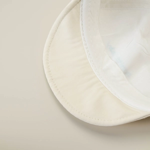 Detailed close-up of stitching on beige cotton kids' soft-brim baseball cap