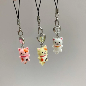 Close-up of cute Y2K kitten phone charms in pink, yellow, and white resin finishes