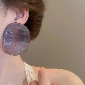 Macro shot of large purple translucent resin earrings with irregular brushed texture