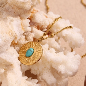 Detailed close-up of 18K gold-plated necklace with turquoise pendant on white coral stone