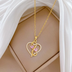 Detail of golden double heart necklace with pink gems and crystals on silk fabric