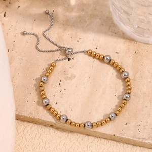 Adjustable two-tone beaded bracelet in 18K gold and silver plating on marble surface