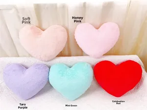 Vue détaillée de coussins en peluche en forme de cœur en rose, violet, vert et rouge
