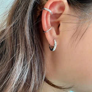 Macro view of textured S925 silver hoop and ear cuffs with hammered lava finish