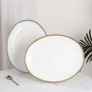Detail of white ceramic plates with textured surface and metallic beaded edges