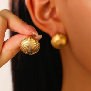 Macro view of gold scallop shell earrings with detailed textured stripes on metal