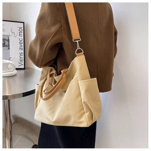 Detail of high-capacity canvas shoulder bag with functional side pockets and woven strap