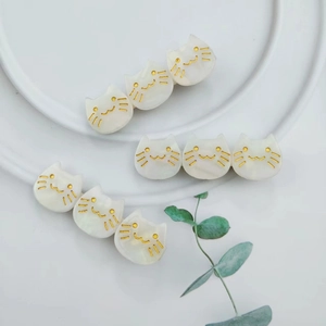 Detailed close-up of cute white acetate cat hair clips on a ceramic plate with green leaves